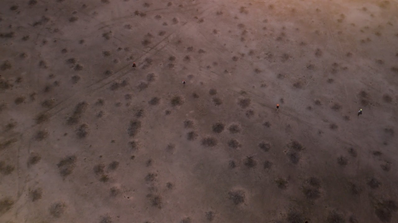 Aerial shot of 4 people walking through the desert